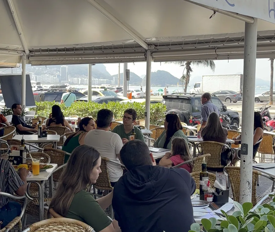 Salão do Hera Bar e Botequim cheio, sob o toldo da calçada